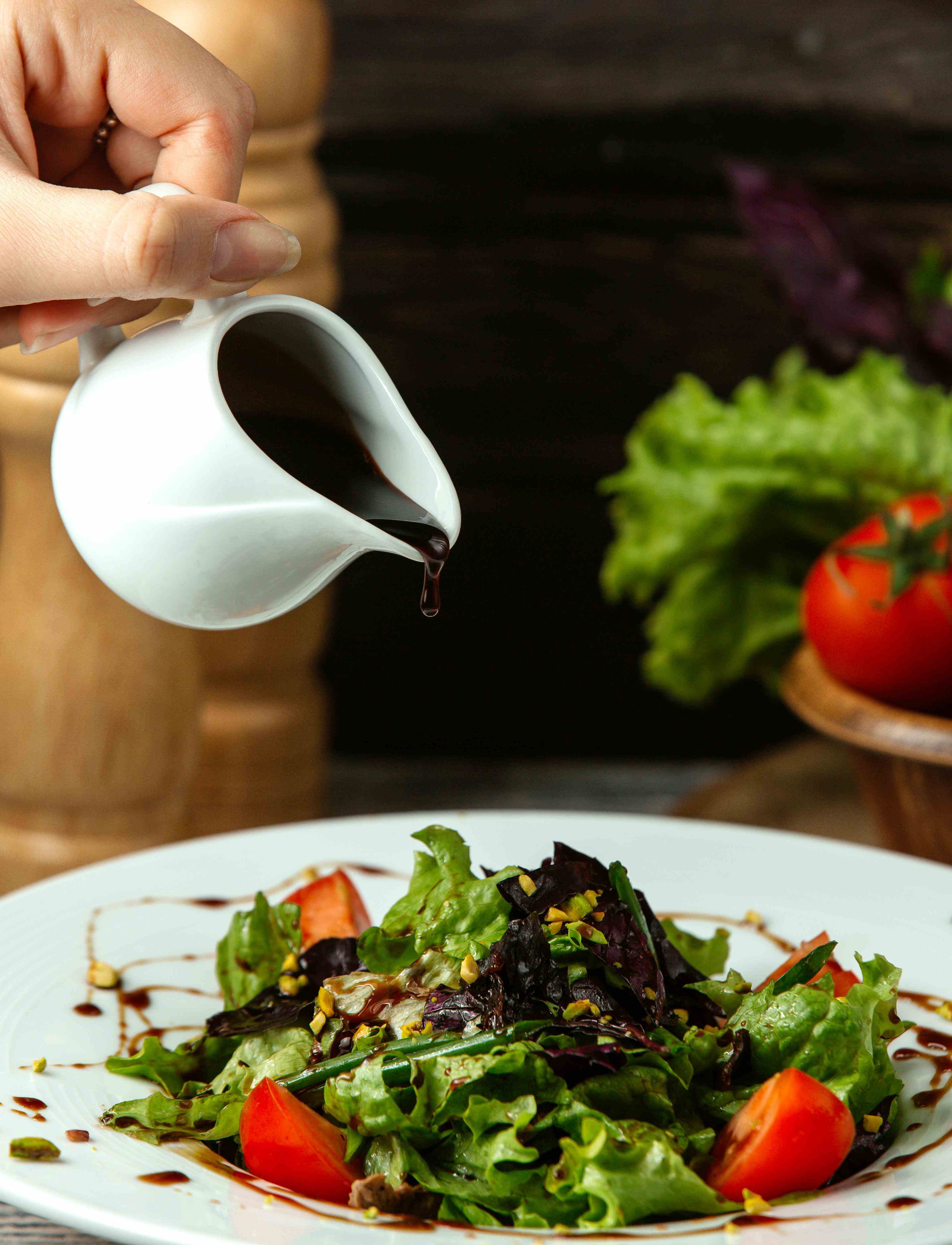 Tuscan Herb Vinaigrette pouring on salad with tomato