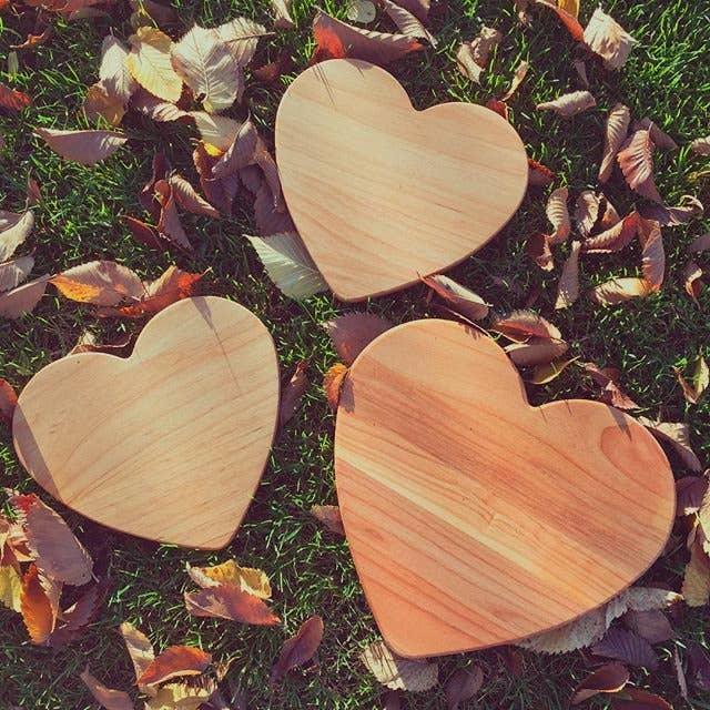Three Redstone heart-shaped hardwood serving boards on grass with autumn leaves — perfect Valentine's Day, anniversary, and wedding gift