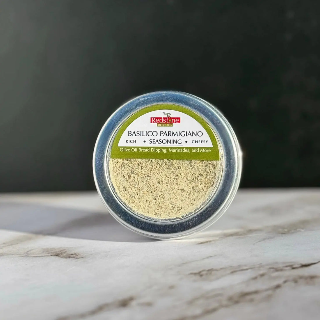 Basilico Parmigiano seasoning blend in a round tin on marble surface