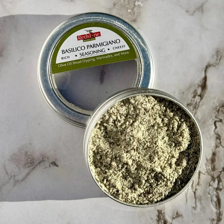 Basilico Parmigiano seasoning blend in an open tin on a marble surface.