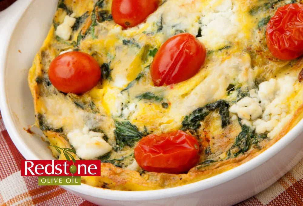 Spinach and feta quiche with tomatoes in a white dish, featuring Redstone Olive Oil branding.