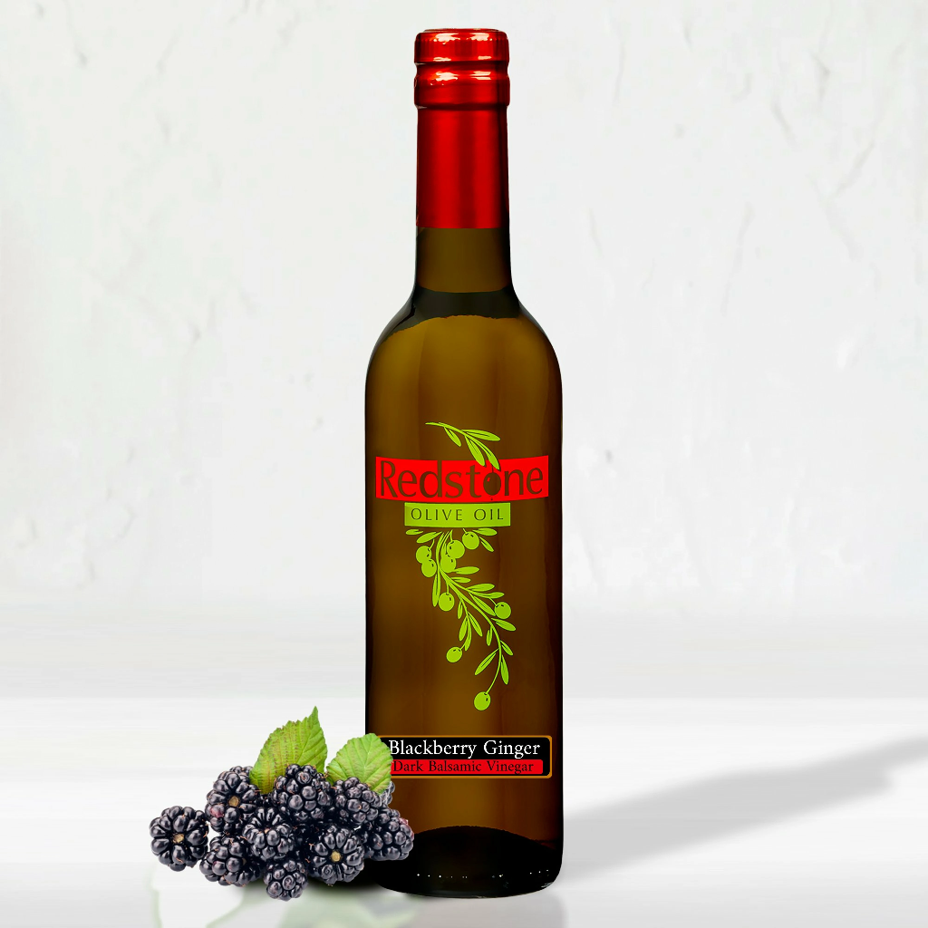 Close-up of Blackberry Ginger Balsamic Vinegar bottle with fresh blackberries in background