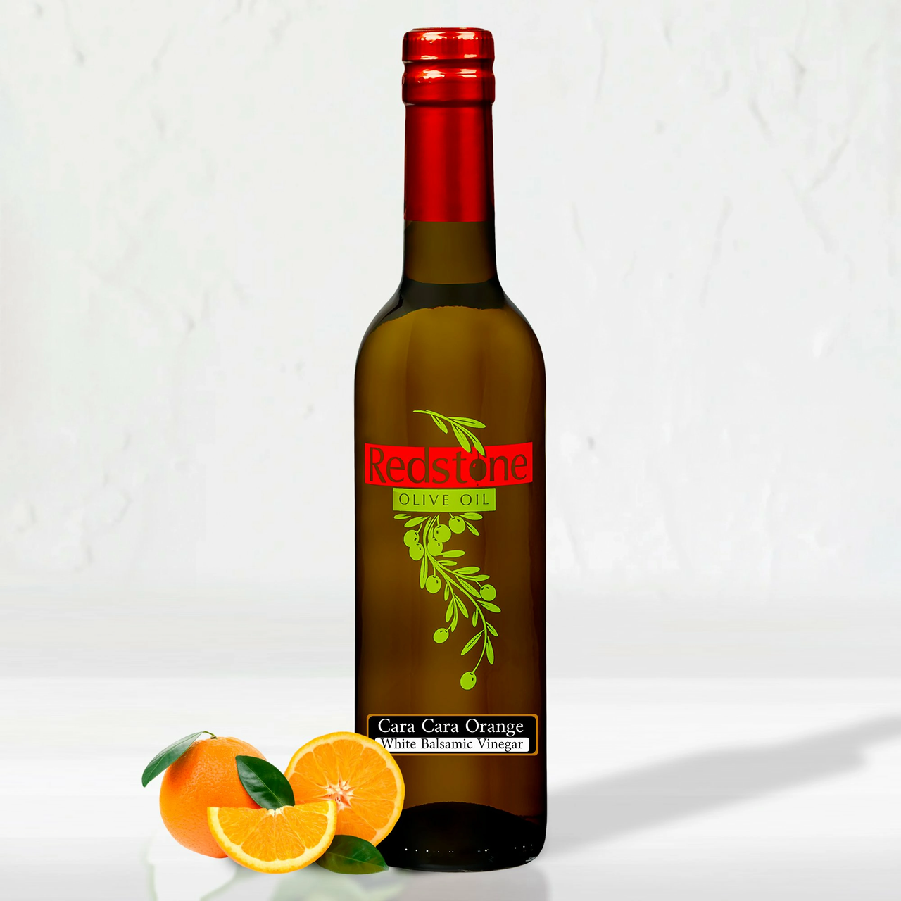 Single bottle of Cara Cara Orange Vanilla White Balsamic Vinegar surrounded by fresh oranges and greenery