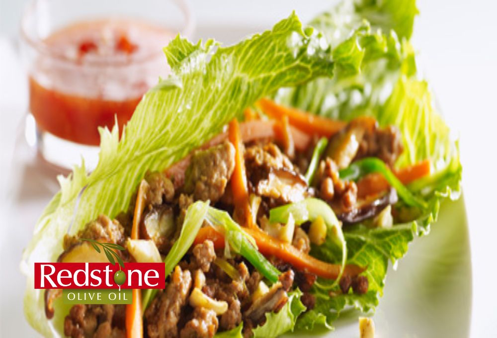 Lettuce wrap with meat and vegetables on a white plate, featuring Redstone Olive Oil logo.