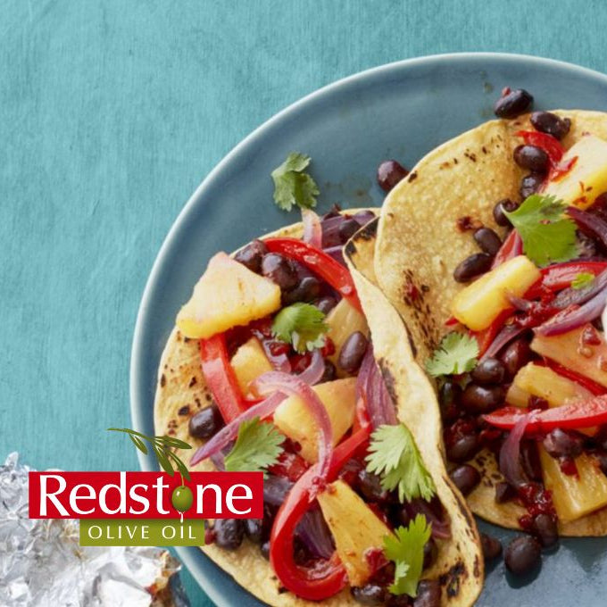 Tacos with pineapple and black beans on a blue plate with Redstone Olive Oil branding.