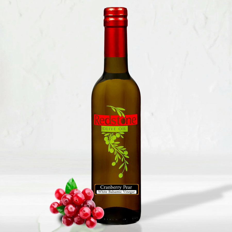 A bottle of Cranberry Pear White Balsamic Vinegar with cranberries on the side