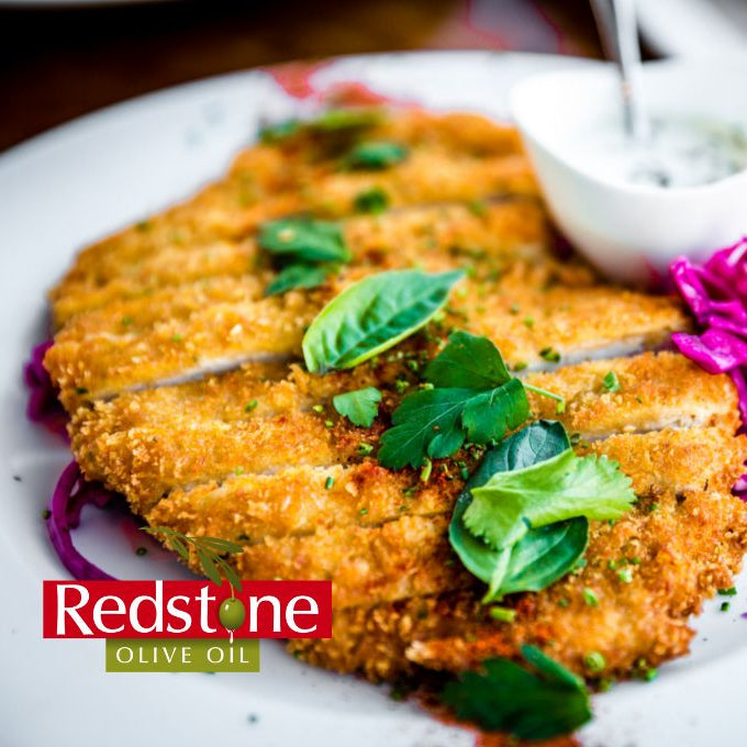 Crispy fried dish with greens and purple cabbage on a white plate, featuring Redstone Olive Oil logo.