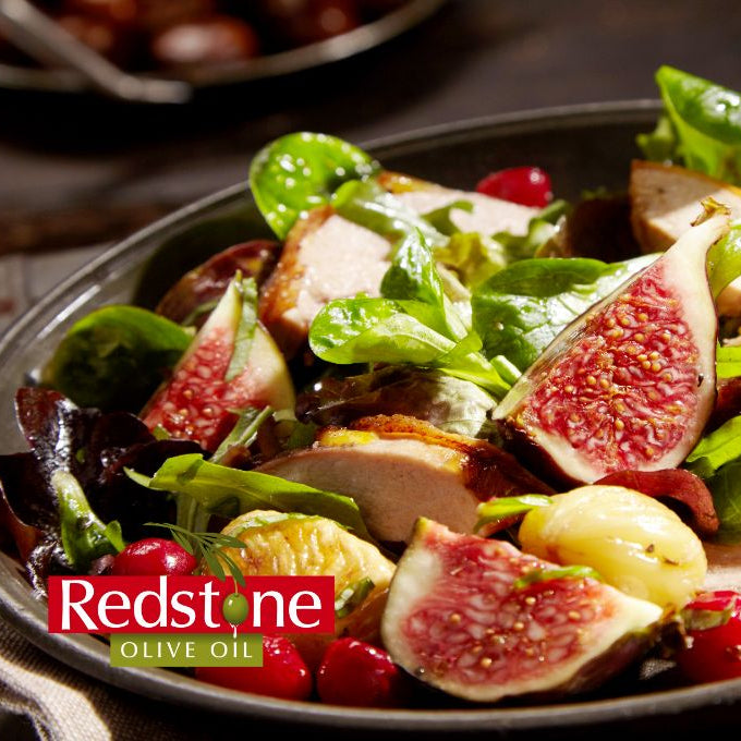 Salad with figs, chicken, and vegetables on a plate with Redstone Olive Oil branding.