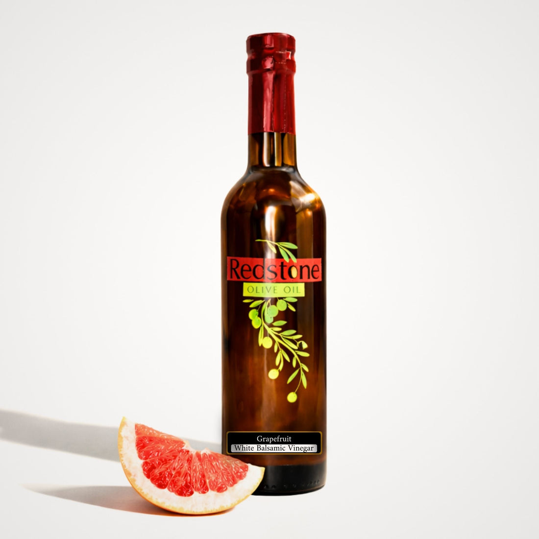 Bottle of grapefruit white balsamic vinegar with a fresh grapefruit slice on white background
