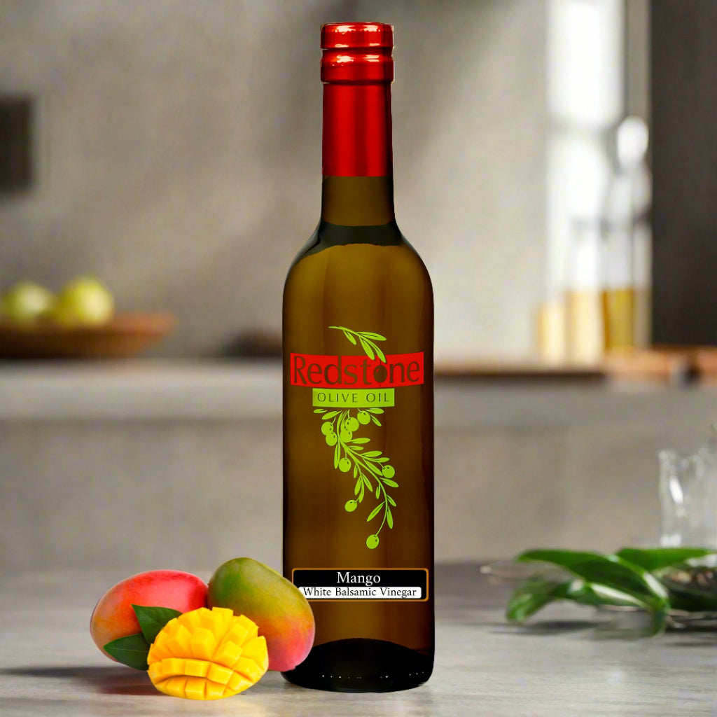 Close-up of Mango White Balsamic Vinegar bottle with mango fruit in the background