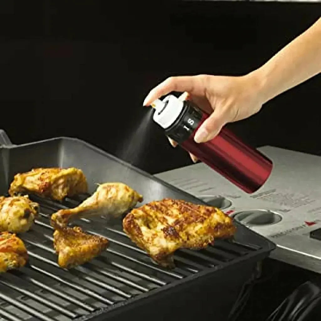 Using the Misto olive oil sprayer to mist chicken on a BBQ grill — perfect for grilling with olive oil