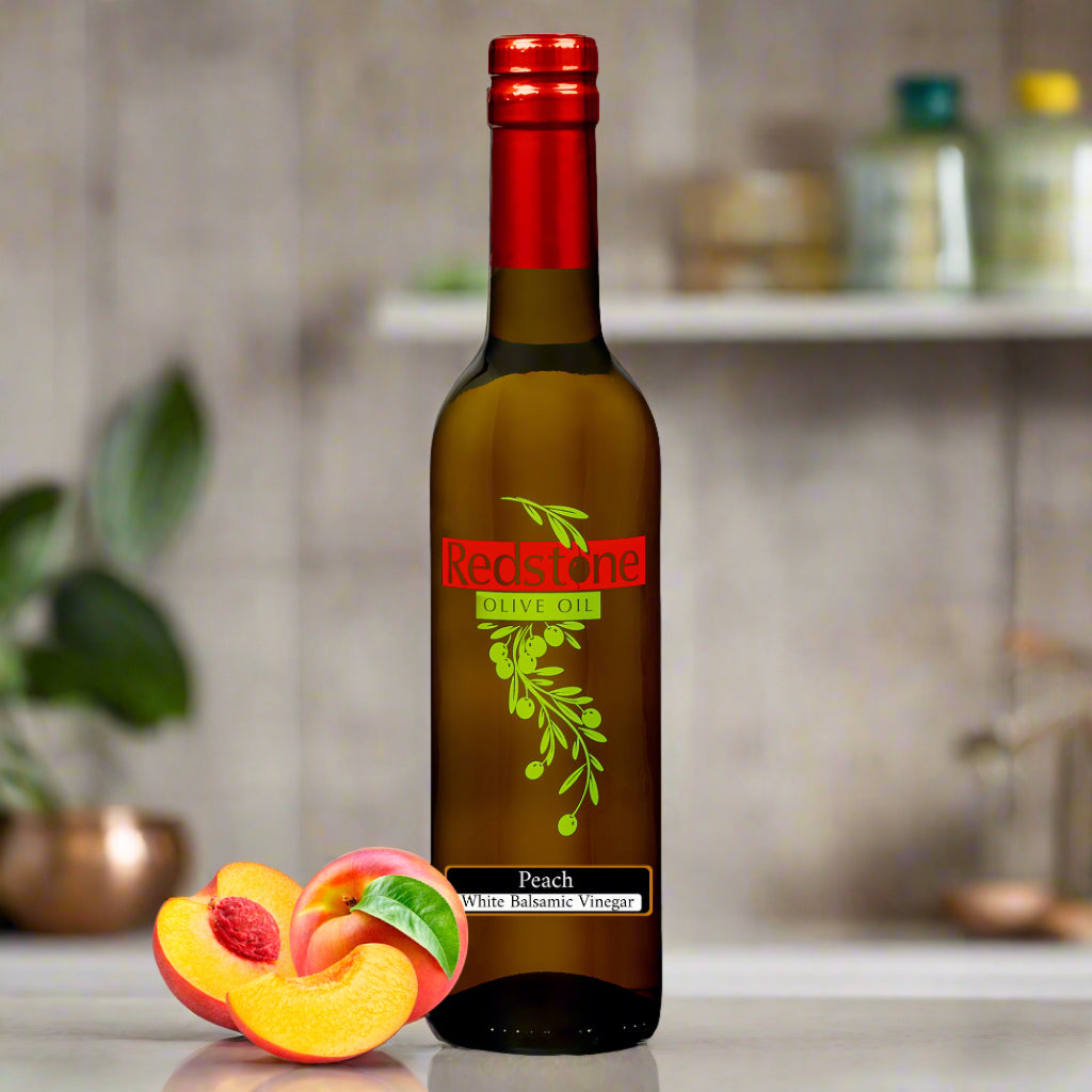 Close-up of Peach White Balsamic Vinegar bottle in kitchen with peach fruit in the background