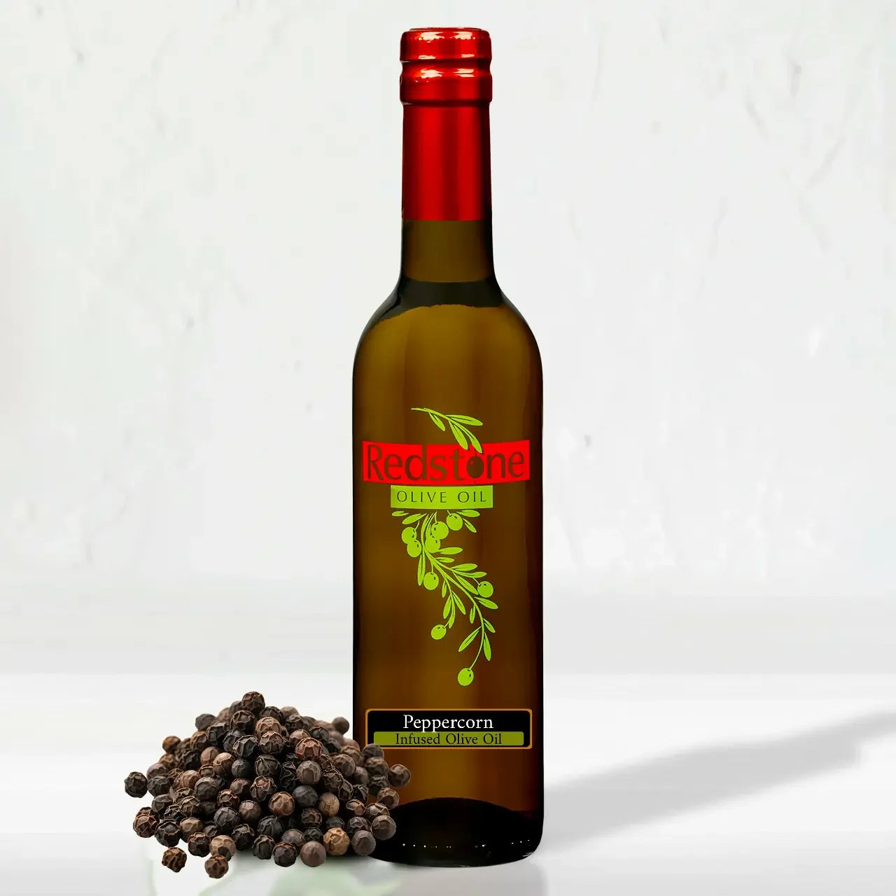 Peppercorn infused extra virgin olive oil by Redstone Olive Oil, styled with a pile of whole black peppercorns on a white background