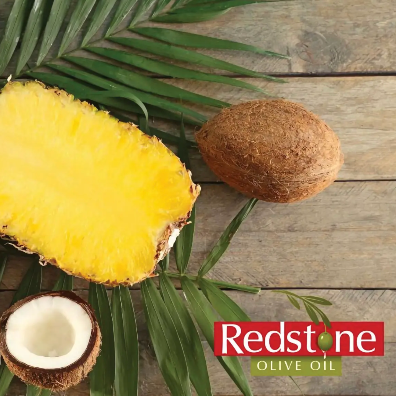 Sliced pineapple and coconuts on a wooden surface with Redstone Olive Oil logo.