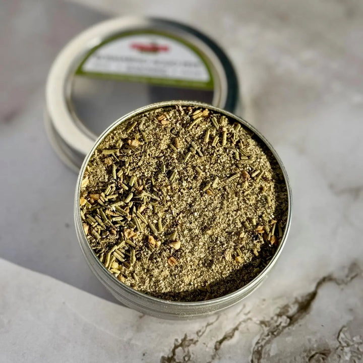 Close-up of dried rosemary herb seasoning in an open tin on a marble surface