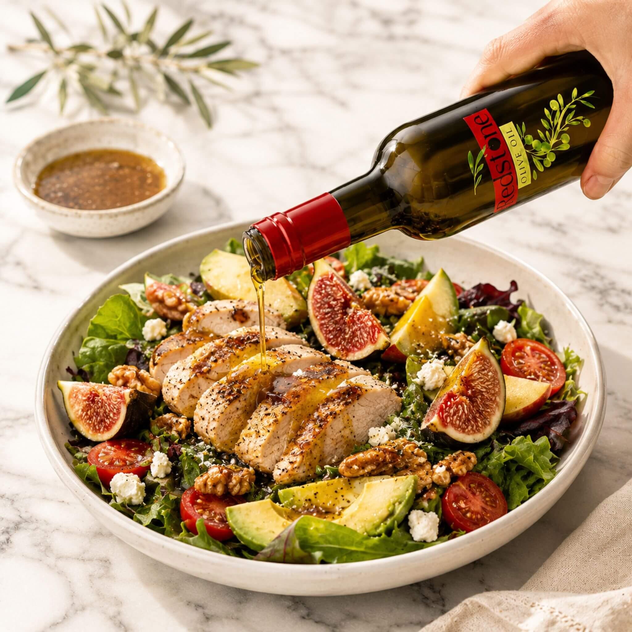Drizzling extra virgin olive oil over a fresh salad with chicken, figs, and avocado