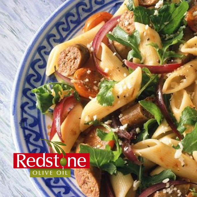 Pasta salad with vegetables on a plate, featuring Redstone Olive Oil branding.