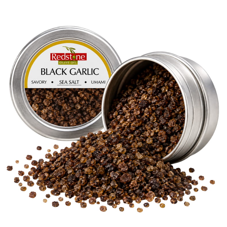 Redstone Black Garlic Sea Salt open tin spilling deep dark garlic-infused sea salt crystals — all-natural gourmet finishing salt