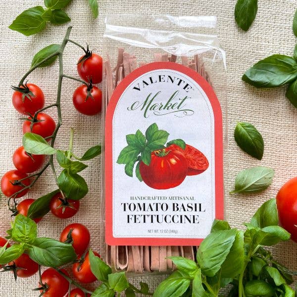 Tomato basil fettuccine pasta package with fresh tomatoes and basil leaves on a linen surface