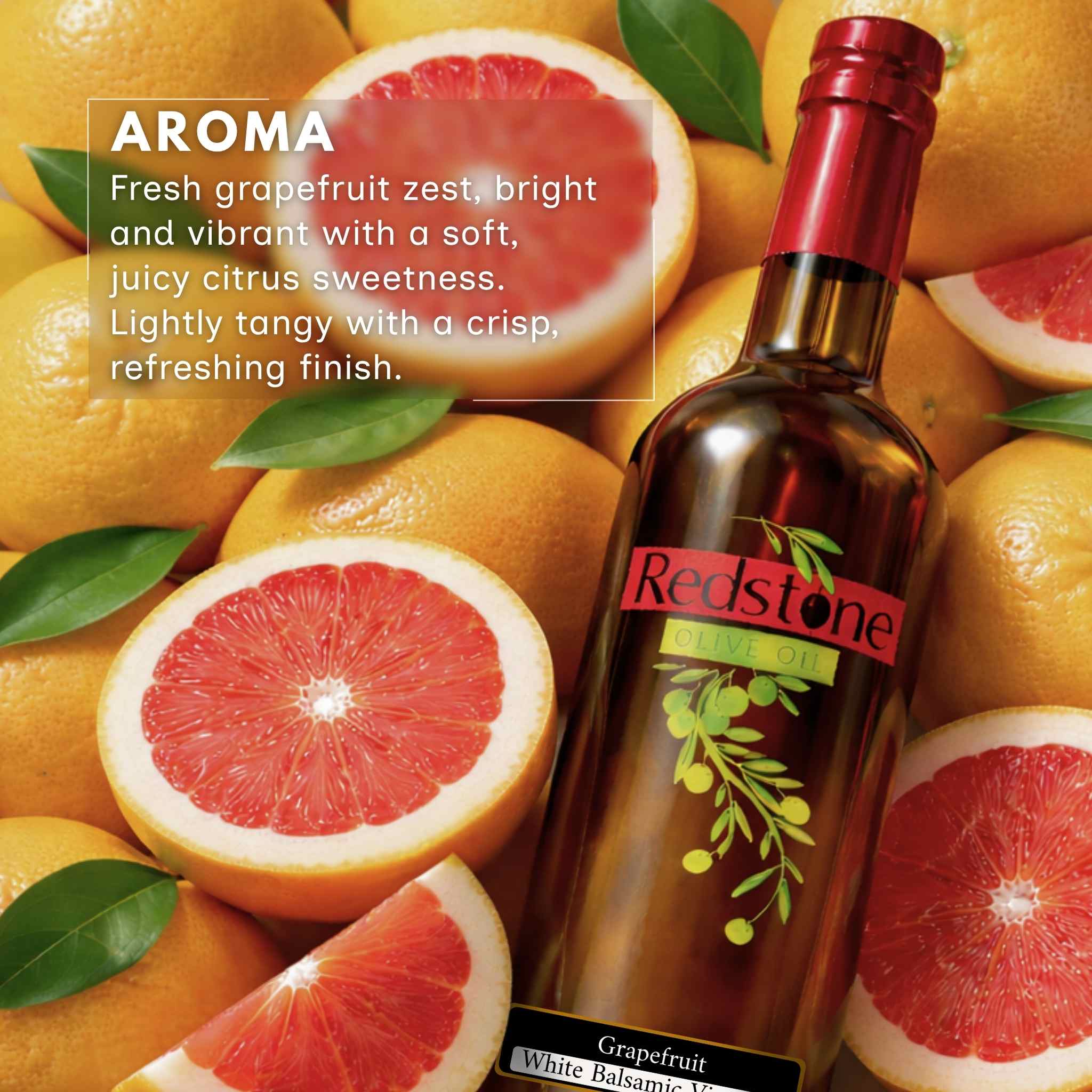 Bottle of olive oil with Redstone label surrounded by fresh grapefruits and green leaves