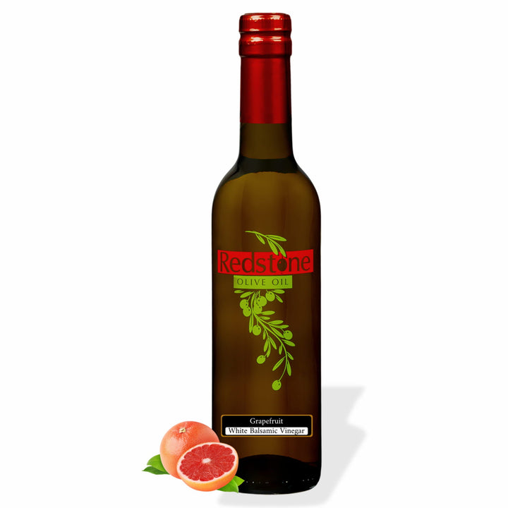 Bottle of Redstone Grapefruit White Balsamic Vinegar with a whole and halved ruby red grapefruit and leaves