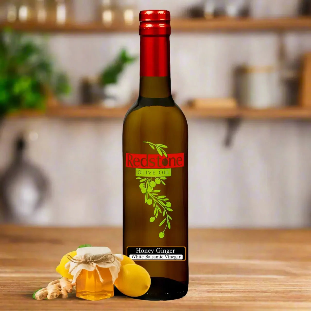Bottle of Redstone Honey Ginger White Balsamic Vinegar with a honey jar, lemons, and ginger root on a kitchen counter