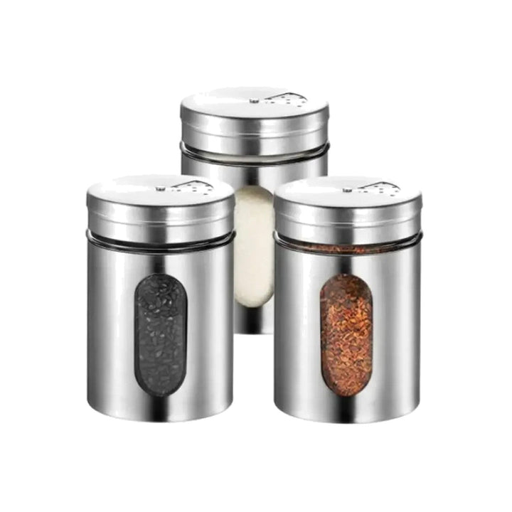 Three stainless steel spice shaker jars filled with black sesame seeds, salt, and red pepper flakes